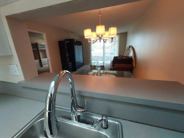 kitchen with a sink, hanging light fixtures, light countertops, and a notable chandelier