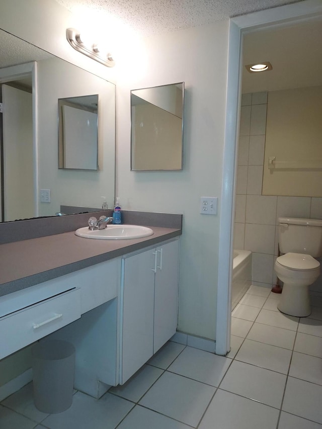 bathroom with tile patterned floors, a textured ceiling, toilet, vanity, and tile walls