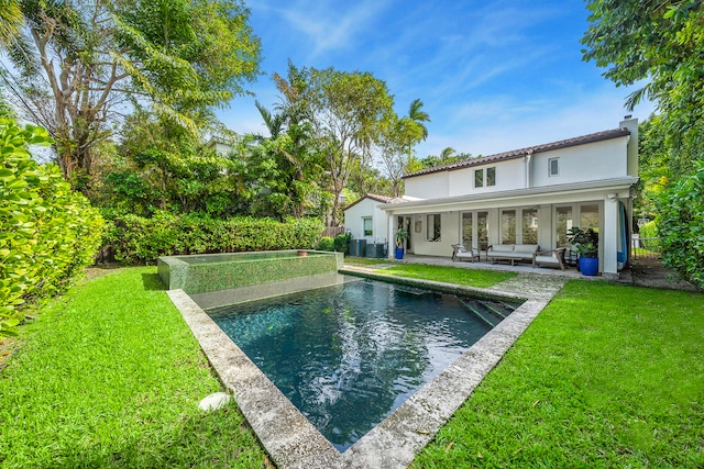 back of property featuring a lawn, outdoor lounge area, and a patio