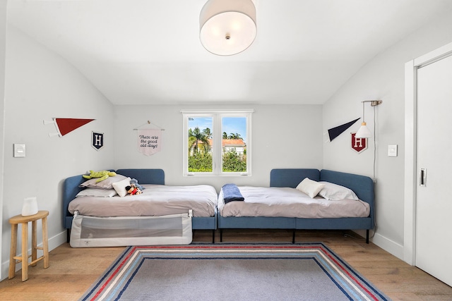 bedroom featuring lofted ceiling and light hardwood / wood-style flooring