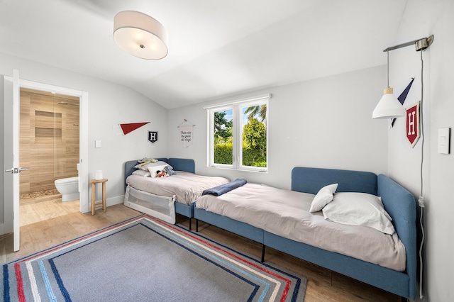 bedroom with hardwood / wood-style floors, ensuite bathroom, and lofted ceiling