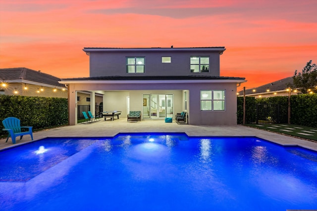 pool at dusk with a patio area