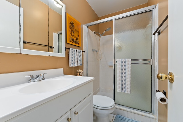 bathroom featuring tile patterned flooring, vanity, toilet, and a shower with shower door