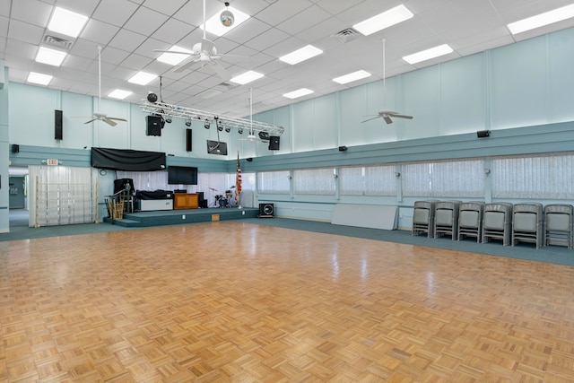 miscellaneous room with a drop ceiling, a towering ceiling, and light parquet flooring