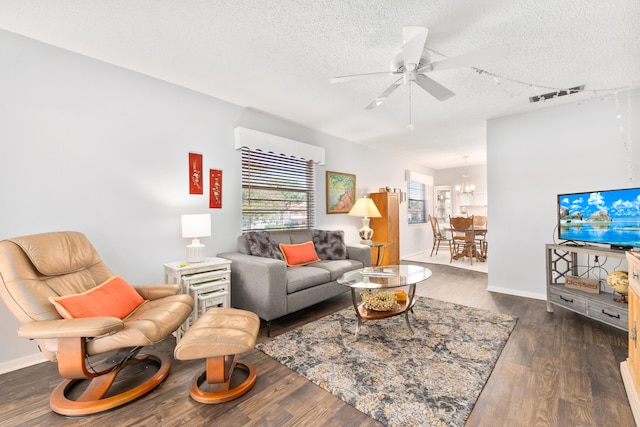 living room with ceiling fan with notable chandelier, a textured ceiling, and dark hardwood / wood-style floors