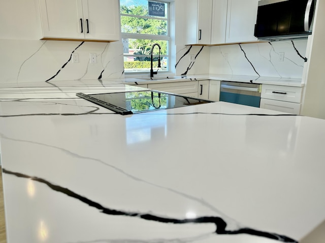 kitchen with white cabinets, dishwashing machine, decorative backsplash, and a sink