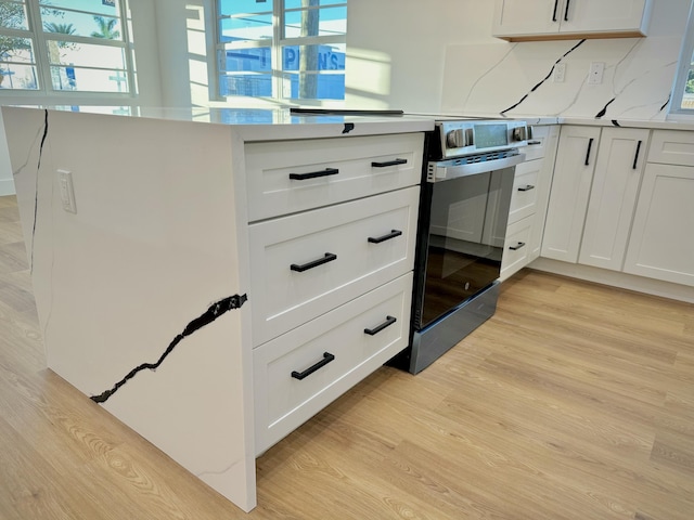 details with light wood-style flooring, light countertops, electric range, and decorative backsplash