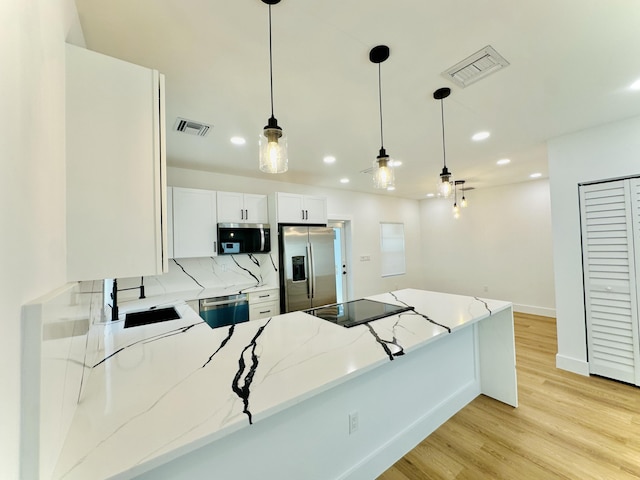 kitchen with appliances with stainless steel finishes, light wood-type flooring, visible vents, and a sink