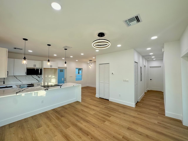 kitchen featuring decorative backsplash, pendant lighting, light hardwood / wood-style floors, and white cabinetry