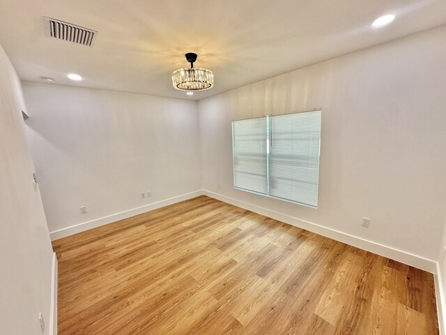 empty room with a chandelier and light hardwood / wood-style flooring