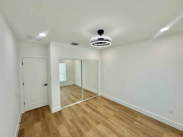 unfurnished bedroom with light wood finished floors, a closet, visible vents, and baseboards