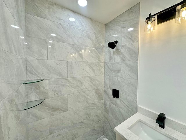 bathroom with tiled shower and sink