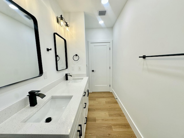 full bathroom with baseboards, visible vents, a sink, and wood finished floors