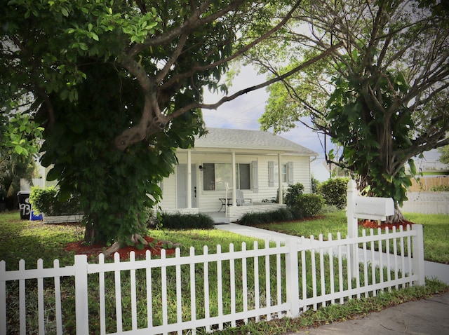 view of front of property featuring a fenced front yard, covered porch, and a shingled roof