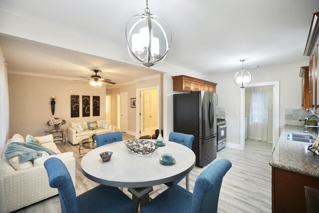 living room with ceiling fan with notable chandelier, light hardwood / wood-style floors, and crown molding