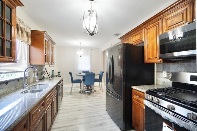 kitchen featuring light wood finished floors, backsplash, glass insert cabinets, a sink, and dishwashing machine