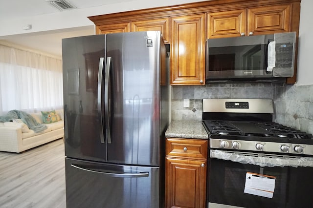 kitchen with brown cabinets, tasteful backsplash, visible vents, and stainless steel appliances