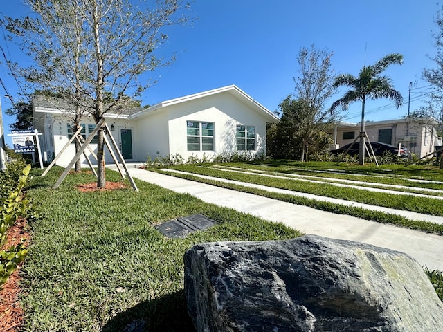 ranch-style home featuring a front yard and stucco siding