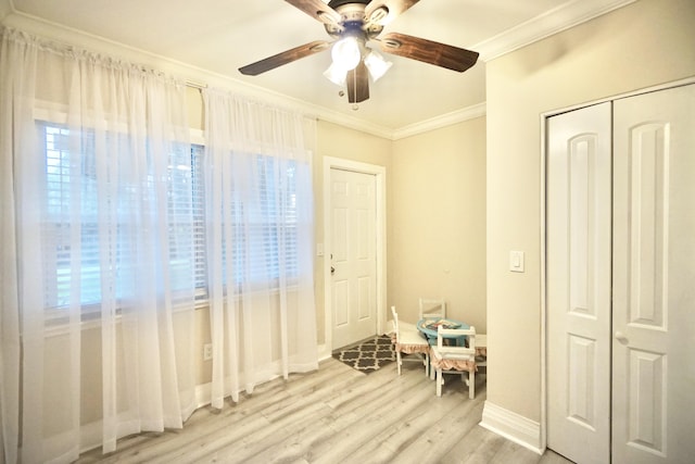 interior space featuring a ceiling fan, baseboards, a closet, light wood-type flooring, and crown molding