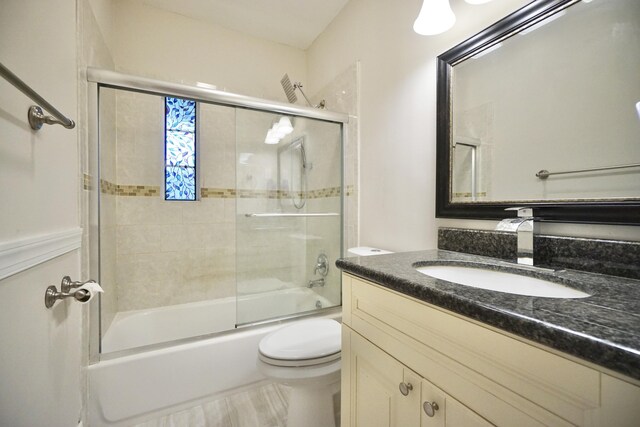 full bathroom featuring toilet, bath / shower combo with glass door, and vanity