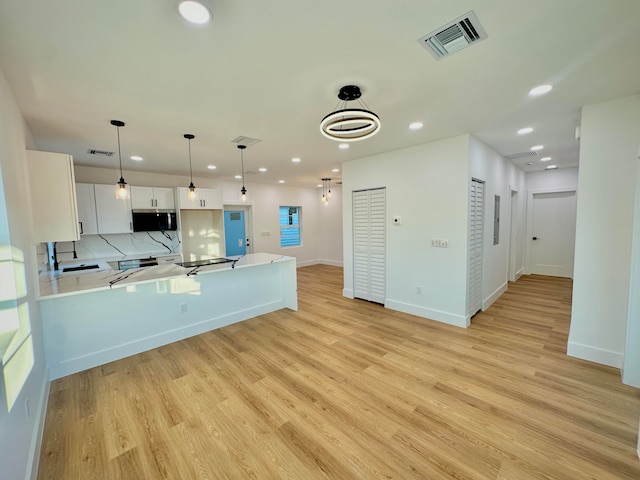 kitchen featuring pendant lighting, sink, light hardwood / wood-style flooring, white cabinetry, and kitchen peninsula