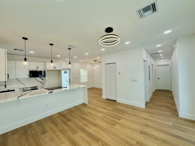 kitchen featuring kitchen peninsula, pendant lighting, white cabinets, and black range with electric stovetop