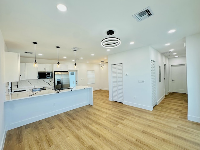 kitchen featuring light countertops, appliances with stainless steel finishes, light wood-type flooring, and visible vents