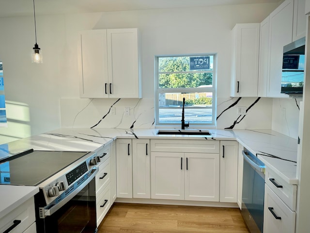 kitchen with sink, stainless steel appliances, backsplash, white cabinets, and light wood-type flooring