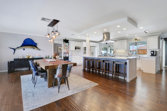 dining area with crown molding and dark wood-type flooring