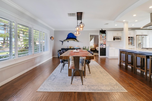 dining room with decorative columns, dark wood-type flooring, and ornamental molding