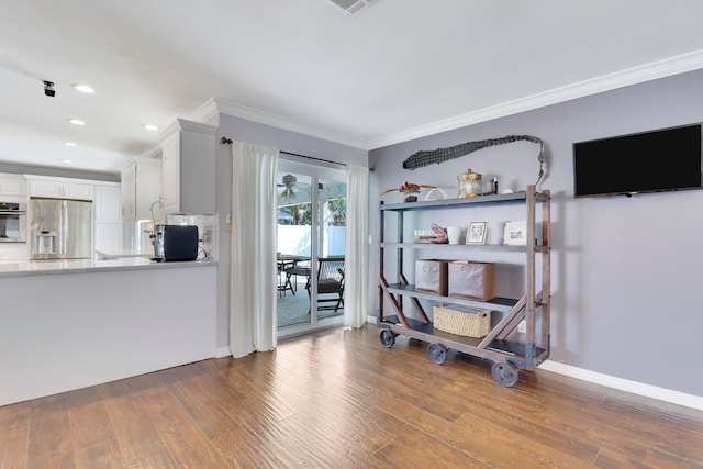 interior space featuring hardwood / wood-style flooring, white cabinetry, crown molding, and appliances with stainless steel finishes