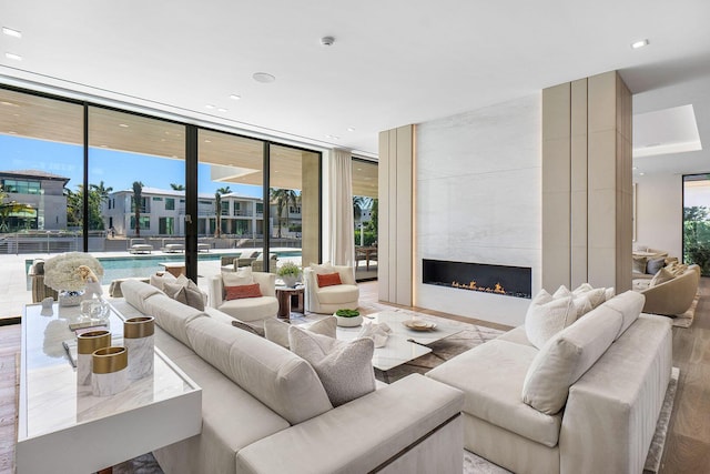 living room featuring a fireplace, light wood-type flooring, and a wall of windows