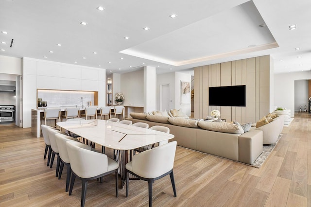 dining room with a tray ceiling and light hardwood / wood-style flooring