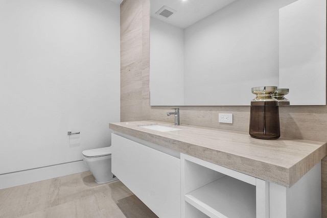 bathroom featuring tasteful backsplash, toilet, vanity, and hardwood / wood-style flooring