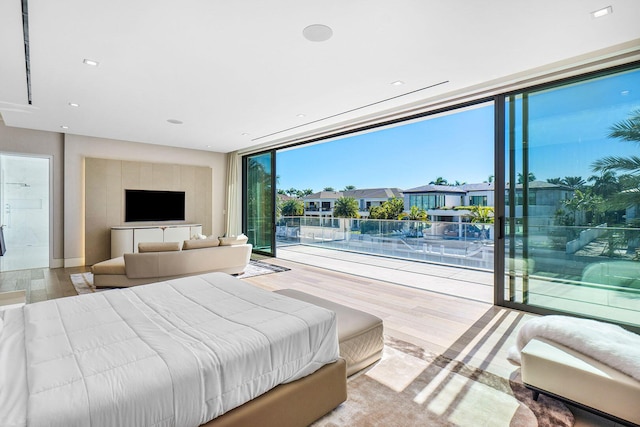 bedroom with floor to ceiling windows and light hardwood / wood-style flooring