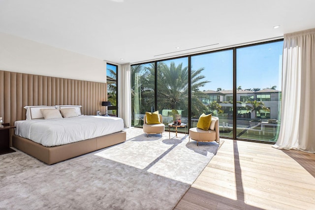 bedroom featuring a wall of windows, hardwood / wood-style flooring, and multiple windows