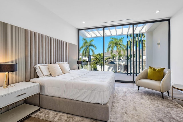 bedroom with expansive windows, wood-type flooring, and access to outside