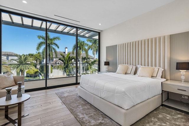 bedroom featuring hardwood / wood-style flooring, expansive windows, access to outside, and multiple windows