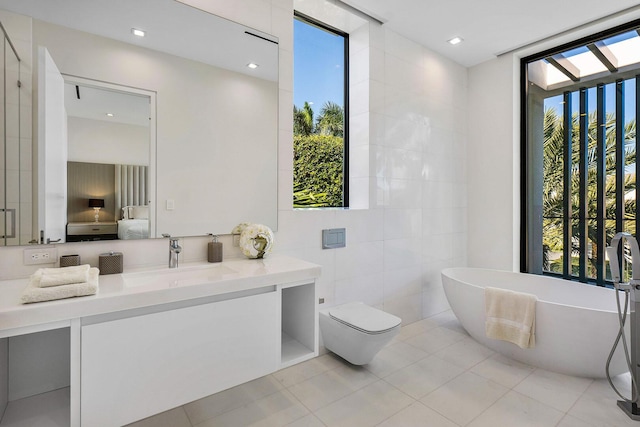 bathroom featuring vanity, tile patterned floors, a washtub, toilet, and tile walls