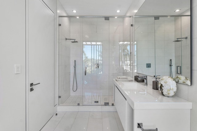 bathroom with tile patterned floors, vanity, a shower with shower door, and tile walls