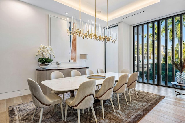 dining room featuring hardwood / wood-style floors, floor to ceiling windows, and a raised ceiling