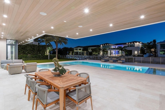 pool at night featuring a patio area