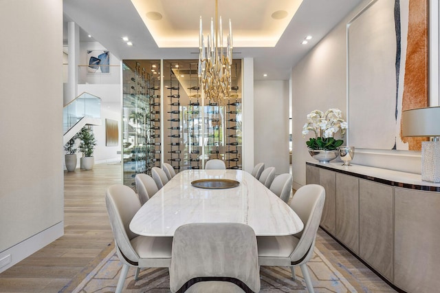 dining room featuring light hardwood / wood-style floors, a raised ceiling, and a notable chandelier