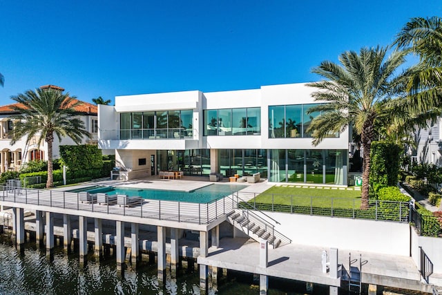 back of house featuring a lawn, an outdoor living space, a patio area, and a water view