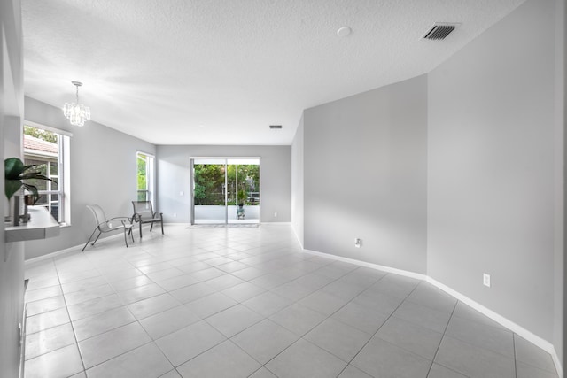 unfurnished room featuring a textured ceiling, plenty of natural light, and light tile patterned flooring