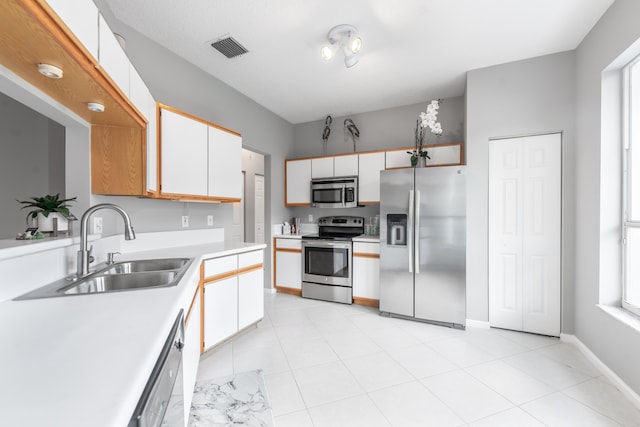 kitchen with white cabinetry, sink, light tile patterned floors, and stainless steel appliances