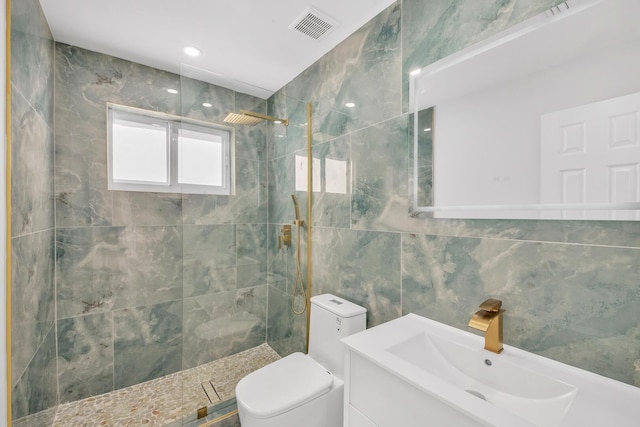 bathroom featuring visible vents, toilet, tile walls, walk in shower, and vanity