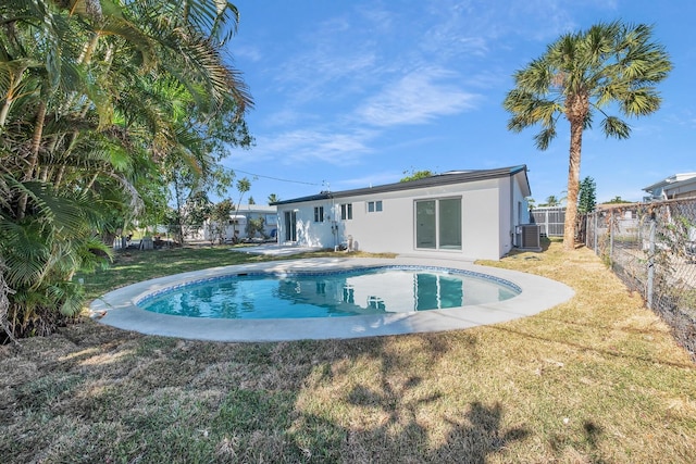 rear view of property with central air condition unit, a lawn, fence, and stucco siding