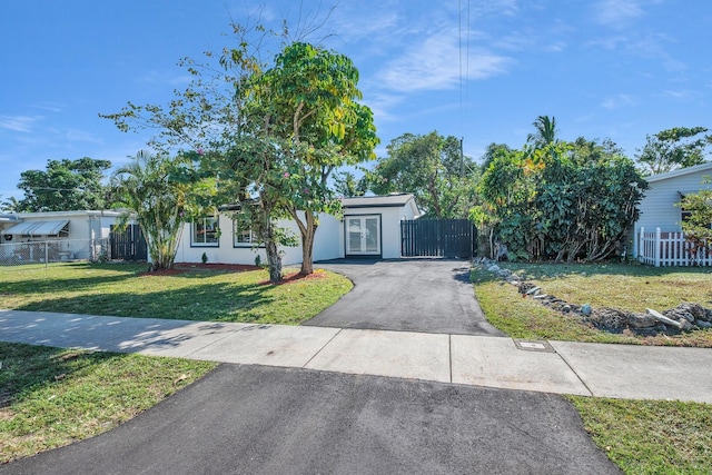 view of front of property featuring stucco siding, a front lawn, driveway, and fence