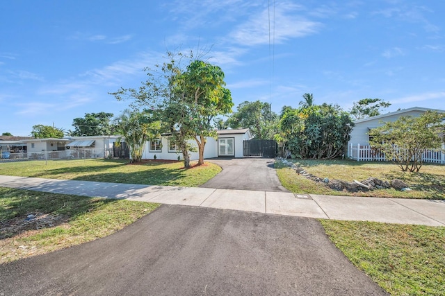 obstructed view of property with driveway, a front yard, and fence